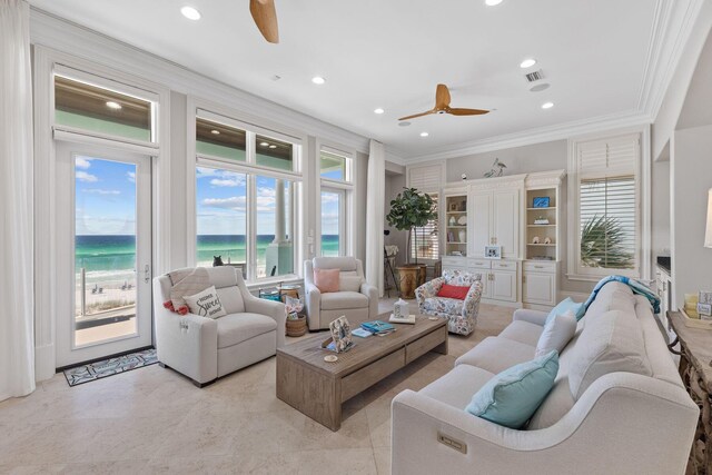 tiled living room with ornamental molding, built in shelves, ceiling fan, and a water view