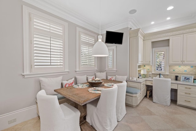 dining room with recessed lighting, baseboards, built in desk, breakfast area, and crown molding