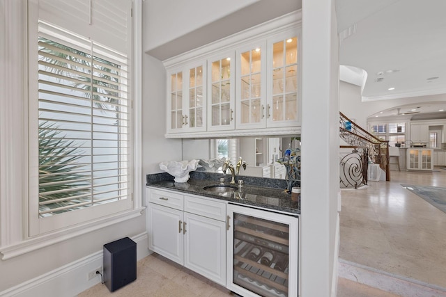 bar with arched walkways, indoor wet bar, a sink, beverage cooler, and stairs