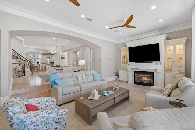 living area with arched walkways, a premium fireplace, visible vents, and a ceiling fan