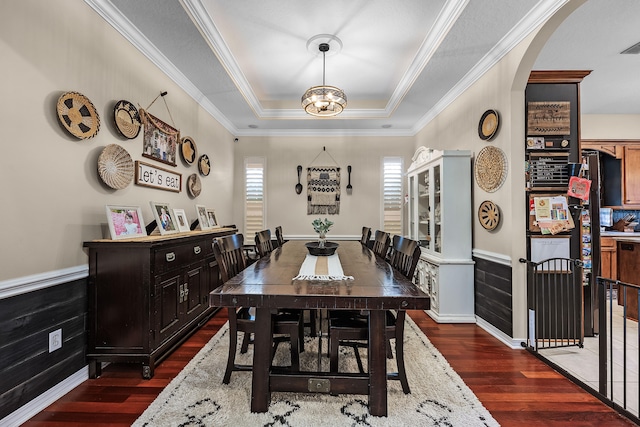 dining room featuring a tray ceiling, crown molding, a notable chandelier, and dark hardwood / wood-style flooring