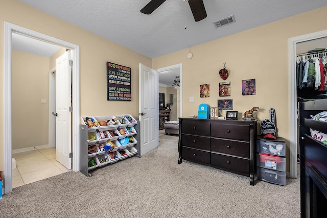 carpeted bedroom featuring ceiling fan, a closet, and a textured ceiling