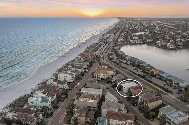 aerial view at dusk featuring a view of the beach and a water view