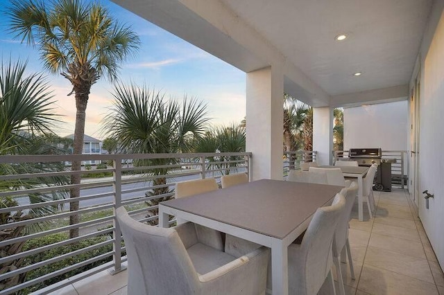 patio terrace at dusk featuring area for grilling and a balcony