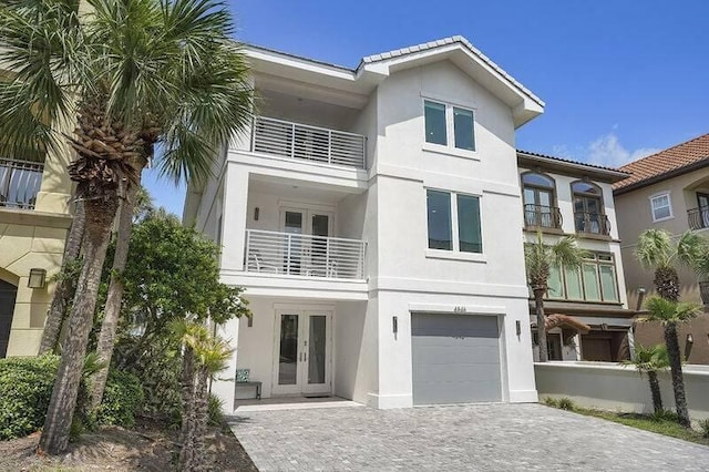 view of front facade featuring a garage, french doors, and a balcony