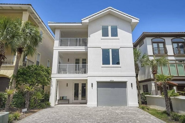 view of front facade with a garage, french doors, and a balcony