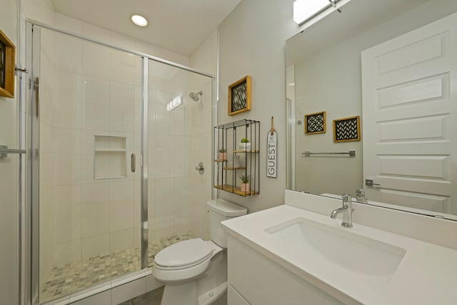 bathroom featuring a shower with shower door, large vanity, and toilet