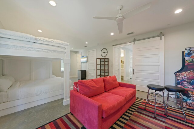 bedroom featuring a barn door, ceiling fan, and concrete flooring