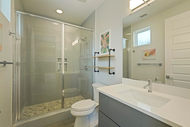 bathroom with a shower with door, vanity with extensive cabinet space, and toilet