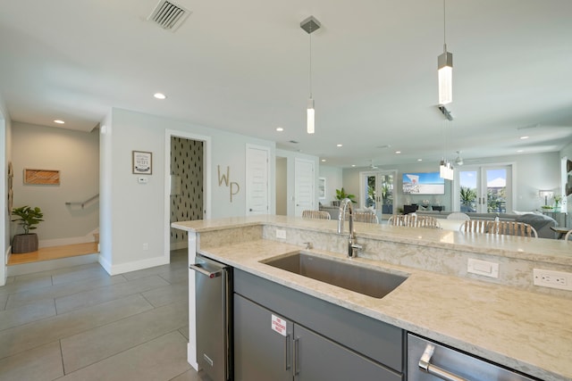 kitchen with tile floors, light stone countertops, stainless steel dishwasher, sink, and pendant lighting