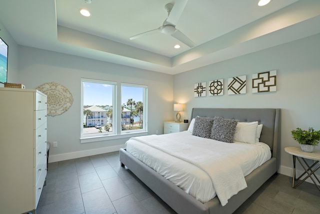 tiled bedroom with ceiling fan and a raised ceiling