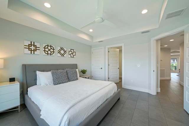 bedroom with dark tile flooring, ceiling fan, and a raised ceiling