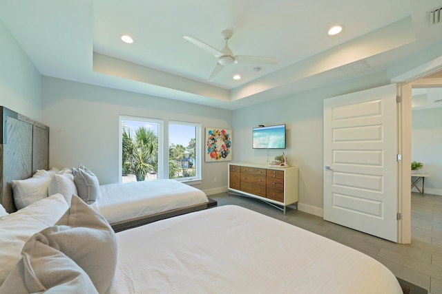 tiled bedroom with ceiling fan and a tray ceiling