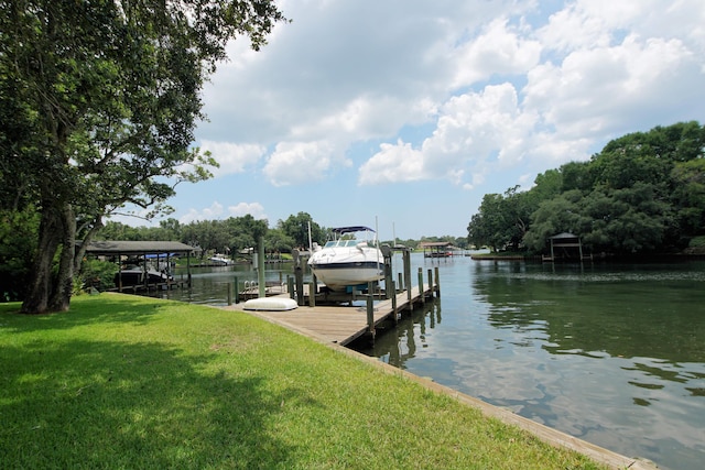 view of dock with a water view, a lawn, and boat lift