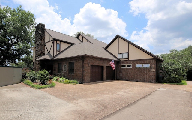 exterior space with driveway, brick siding, a garage, and stucco siding