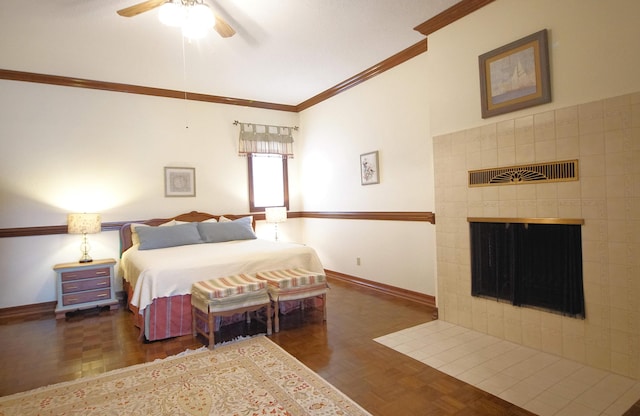 bedroom with ornamental molding, a tiled fireplace, baseboards, and ceiling fan