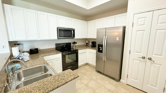 kitchen with white cabinets, appliances with stainless steel finishes, sink, and light stone counters