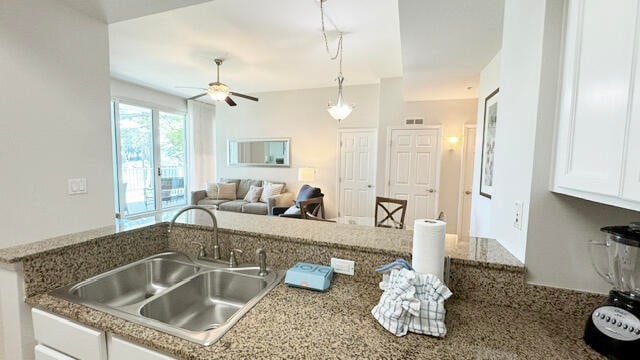 kitchen featuring white cabinetry, stone countertops, pendant lighting, sink, and ceiling fan