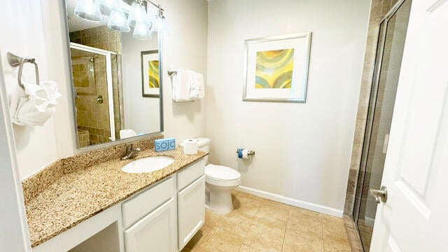 bathroom with tile flooring, an enclosed shower, vanity, and toilet