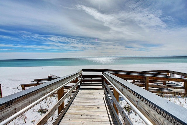 view of dock featuring a beach view and a water view