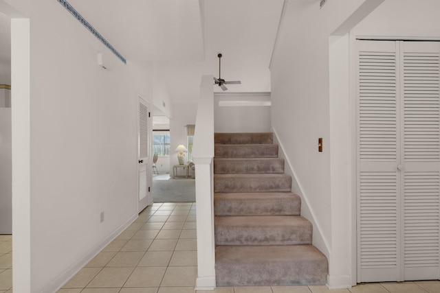 stairway with ceiling fan and light tile floors