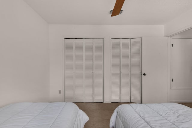 bedroom with two closets, ceiling fan, and carpet floors