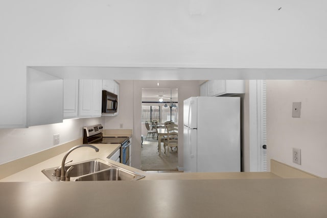 kitchen with sink, stainless steel range with electric stovetop, white cabinets, and white fridge