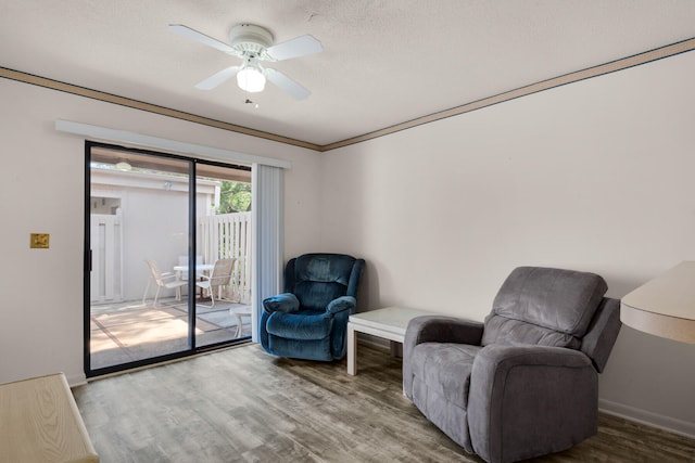 living area with crown molding, a textured ceiling, wood-type flooring, and ceiling fan