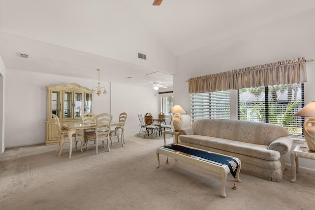 carpeted living room with high vaulted ceiling and ceiling fan with notable chandelier