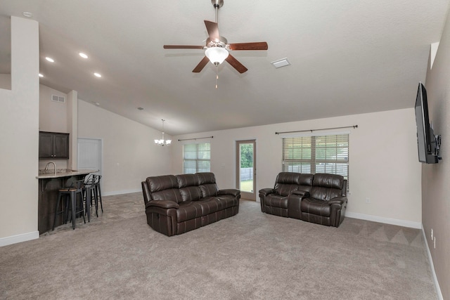 carpeted living room with ceiling fan with notable chandelier, high vaulted ceiling, and sink