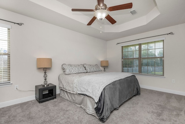 bedroom featuring a tray ceiling, ceiling fan, and light carpet