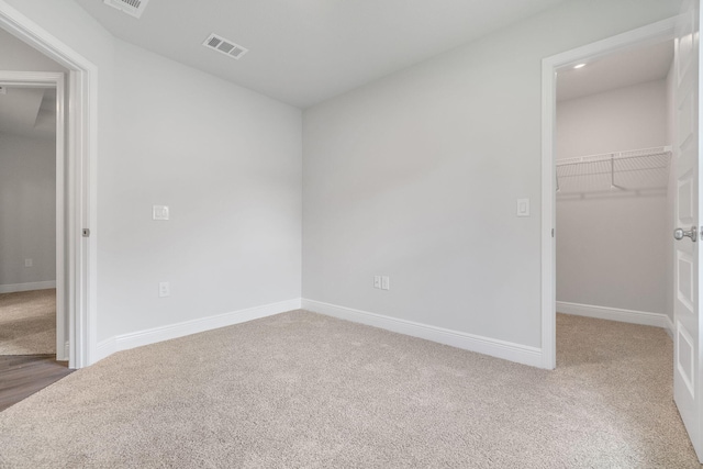 unfurnished bedroom with a spacious closet, carpet flooring, and a closet