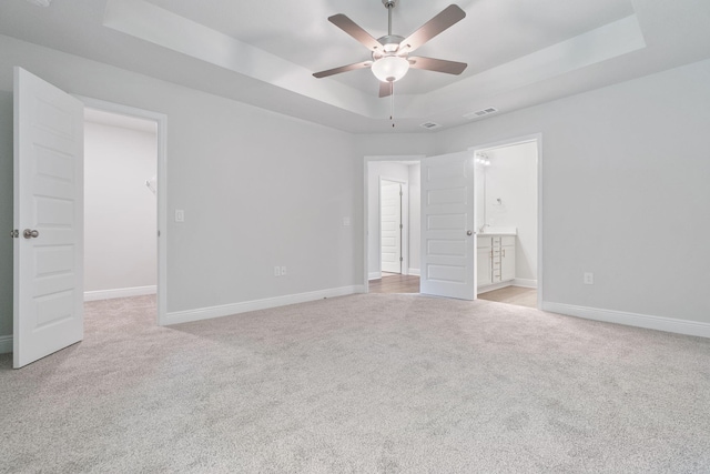 carpeted empty room with ceiling fan and a tray ceiling