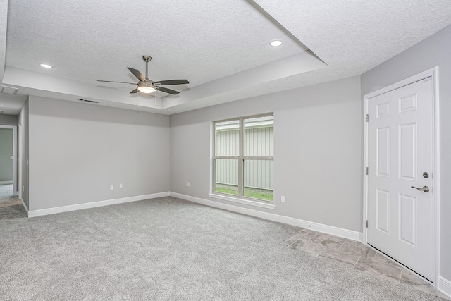 carpeted spare room with a textured ceiling, a raised ceiling, and ceiling fan