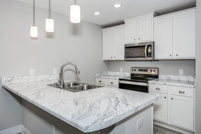 kitchen featuring kitchen peninsula, hanging light fixtures, appliances with stainless steel finishes, white cabinetry, and sink