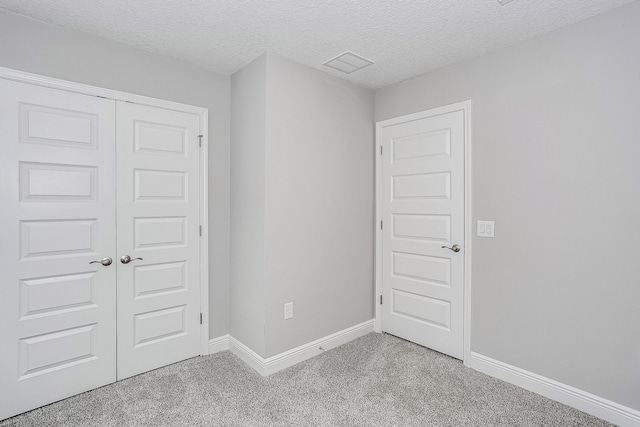 empty room with a textured ceiling and light colored carpet