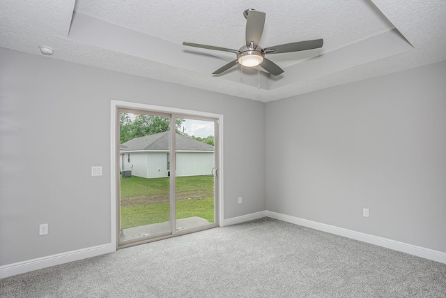 carpeted spare room featuring a raised ceiling, a textured ceiling, and ceiling fan