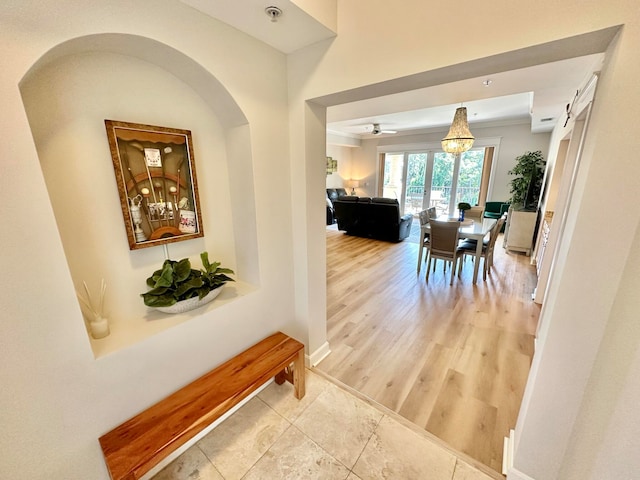 hallway featuring a barn door, hardwood / wood-style flooring, and ornamental molding