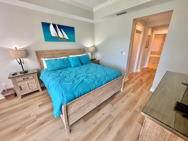 bedroom featuring ensuite bath, light hardwood / wood-style flooring, and ornamental molding