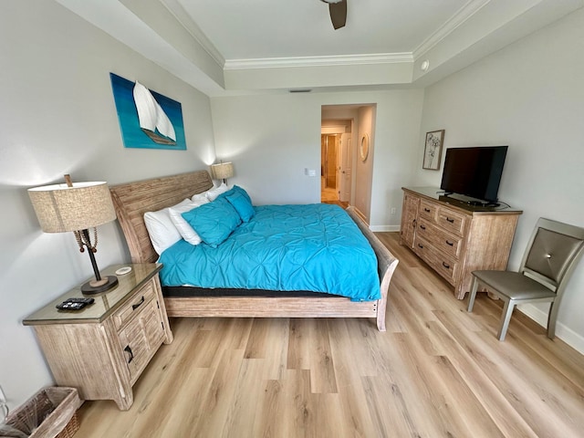 bedroom featuring light hardwood / wood-style floors, ceiling fan, a raised ceiling, and ornamental molding