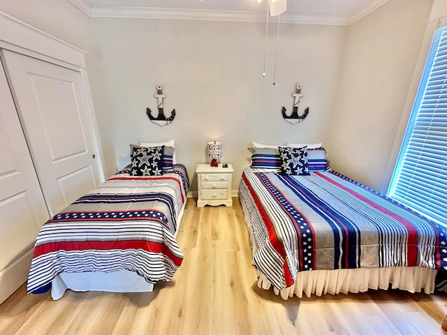 bedroom with a closet, hardwood / wood-style floors, and ornamental molding