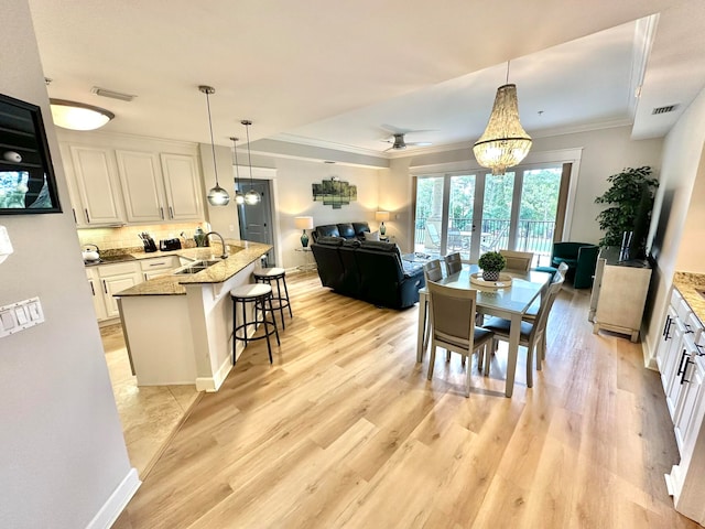 dining area with sink, ceiling fan with notable chandelier, crown molding, and light hardwood / wood-style flooring