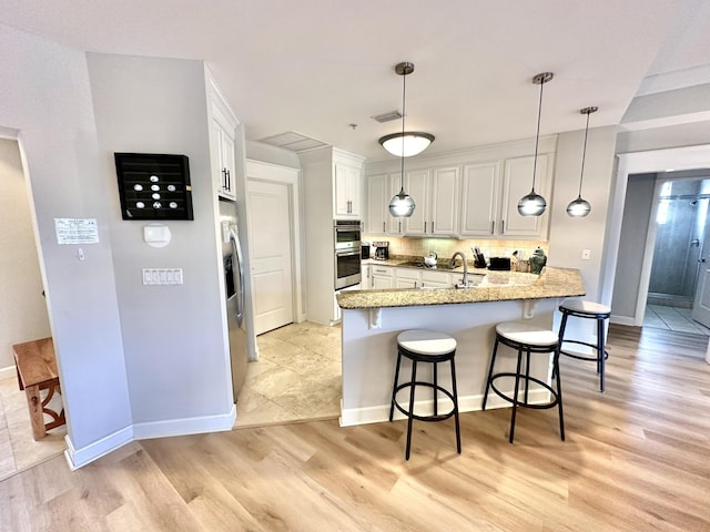 5377 Pine Ridge Ln Unit 5377, Miramar Beach, FL 32550 - kitchen featuring appliances with stainless steel finishes, a peninsula, light wood-style floors, a breakfast bar, and decorative backsplash