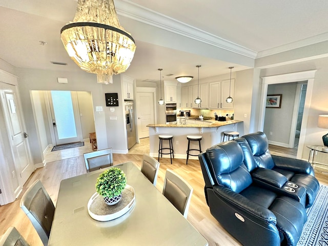 dining space featuring a chandelier, crown molding, and light hardwood / wood-style flooring