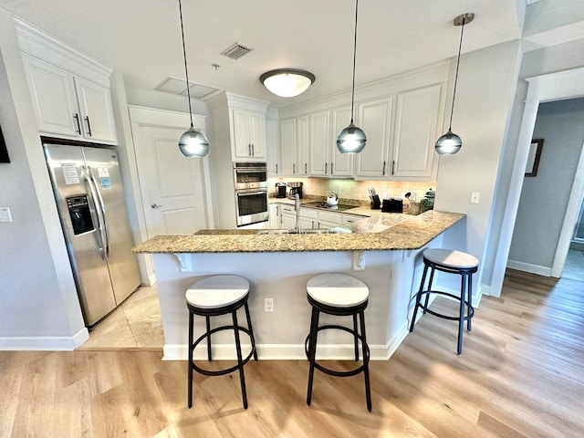 kitchen with light hardwood / wood-style flooring, white cabinetry, kitchen peninsula, and stainless steel appliances