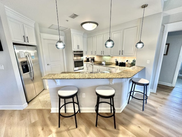 5377 Pine Ridge Ln Unit 5377, Miramar Beach, FL 32550 - kitchen featuring stainless steel appliances, light wood finished floors, decorative backsplash, a breakfast bar, and a peninsula