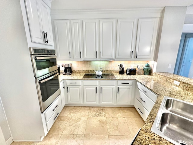 kitchen featuring white cabinets, decorative backsplash, black electric stovetop, and stainless steel double oven