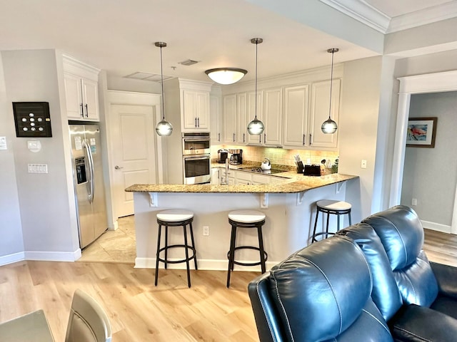 kitchen featuring white cabinets, kitchen peninsula, light hardwood / wood-style flooring, a breakfast bar area, and appliances with stainless steel finishes