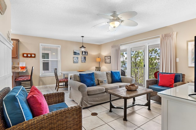 living room with a textured ceiling, ceiling fan, and light tile floors