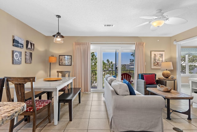 tiled dining area with a textured ceiling and ceiling fan